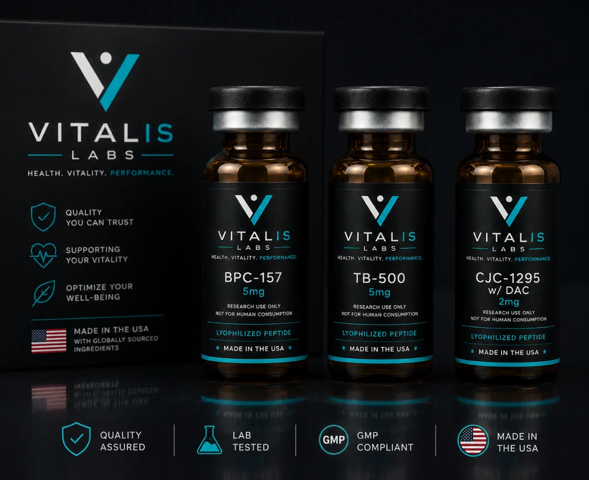 Three amber Vitalis Labs vials standing beside the printed carton panel on a black surface.